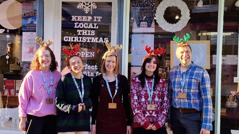 Five people wearing lanyards and standing outside a bookshop