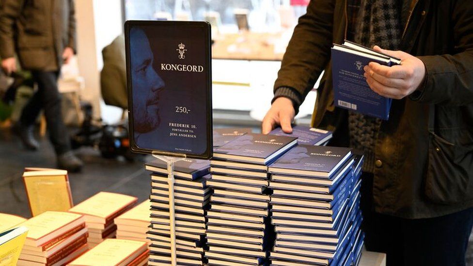 A man holding a copy of the king's book in a bookshop