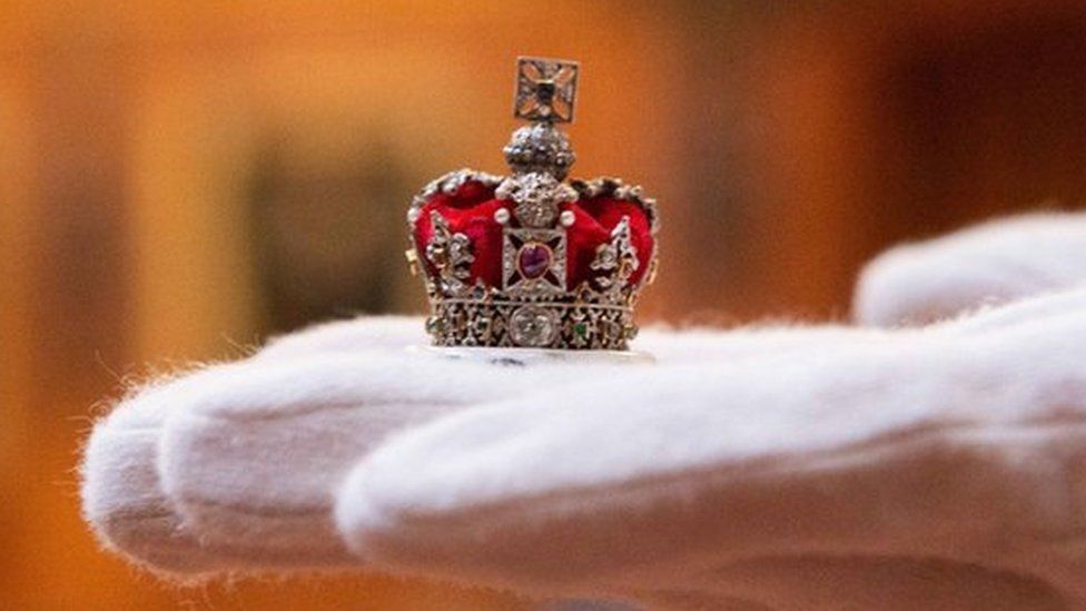 tiny replica of crown jewels held by white glove