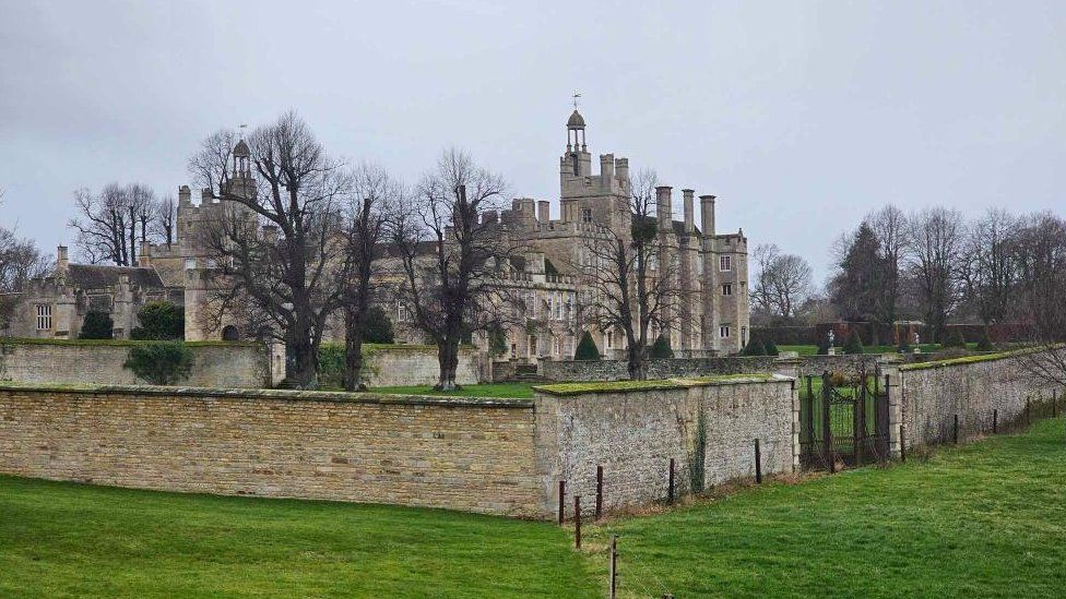 Side view of stone-built stately home with wall around the outside