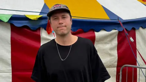 Max Rad smiling in front of a circus festival tent