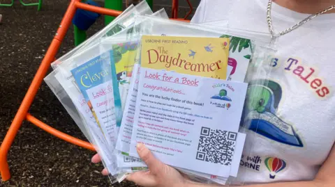 A stack of books in plastic wrapping which will be hidden for kids to find