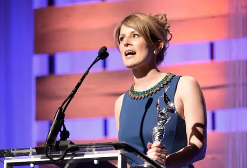 Getty Images Caroline McCall in blue dress accepting award at the Costume Designers Guild Awards