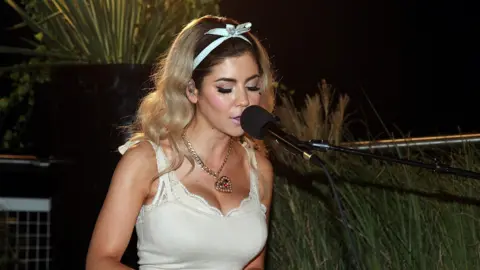 Getty Images Marina Diamandis performing as Marina and the Diamonds, singing at a piano 