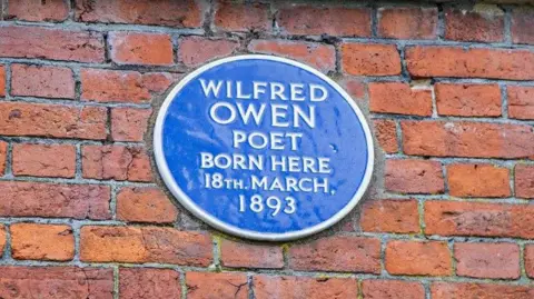 Savills A blue plaque on a brick wall that reads "Wilfred Owen, poet, born here, 18th March, 1893"