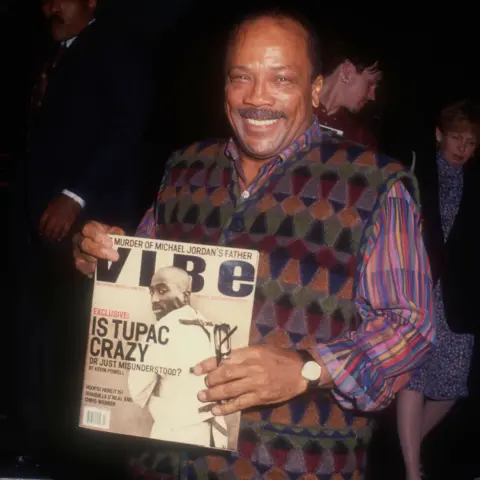 Alamy Quincy Jones holding up a copy of Vibe magazine with Tupac Shakur on the cover and the headline "Is Tupac crazy or just misunderstood?"