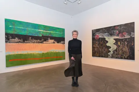 Eva Oertwig, courtesy of News Travels Fast Sharon Stone in Berlin in a black sweater and pleated skirt in front of two large paintings