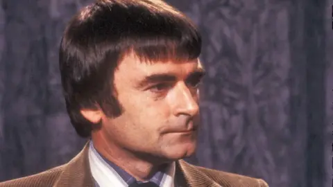 David Lodge wearing a brown suit on the BBC's Book Programme in 1980