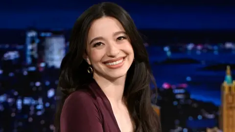 Getty Images Actress Mikey Madison during an interview earlier in January, she is wearing her black hair down and is wearing a chocolate brown top.