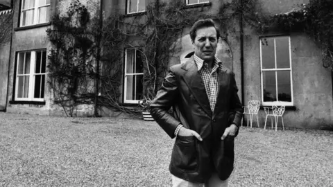 Getty Images Frederick Forsyth is shown in a black and white photo outside his home.