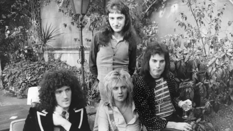 Getty Images Black and white photograph of rock band Queen sat in a courtyard