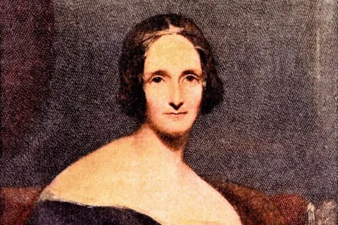 Getty Images A colourised portrait of Mary Shelley. She has very short, bobbed hair and is wearing a black dress with bare shoulders.