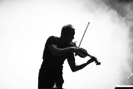 Classical violinist performing on outdoor festival stage with dramatic lighting