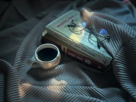 Stack of books with coffee cup on wooden table for cozy reading atmosphere