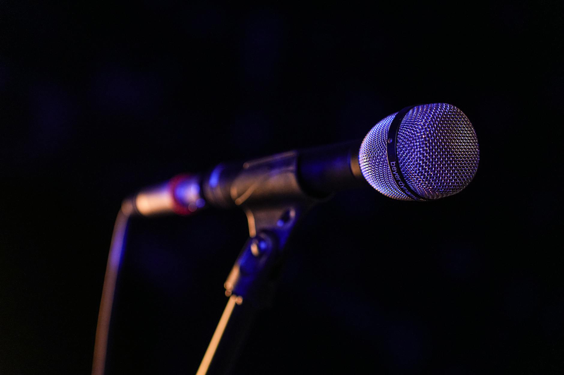 Stand-up comedian performing on stage with microphone under bright lights