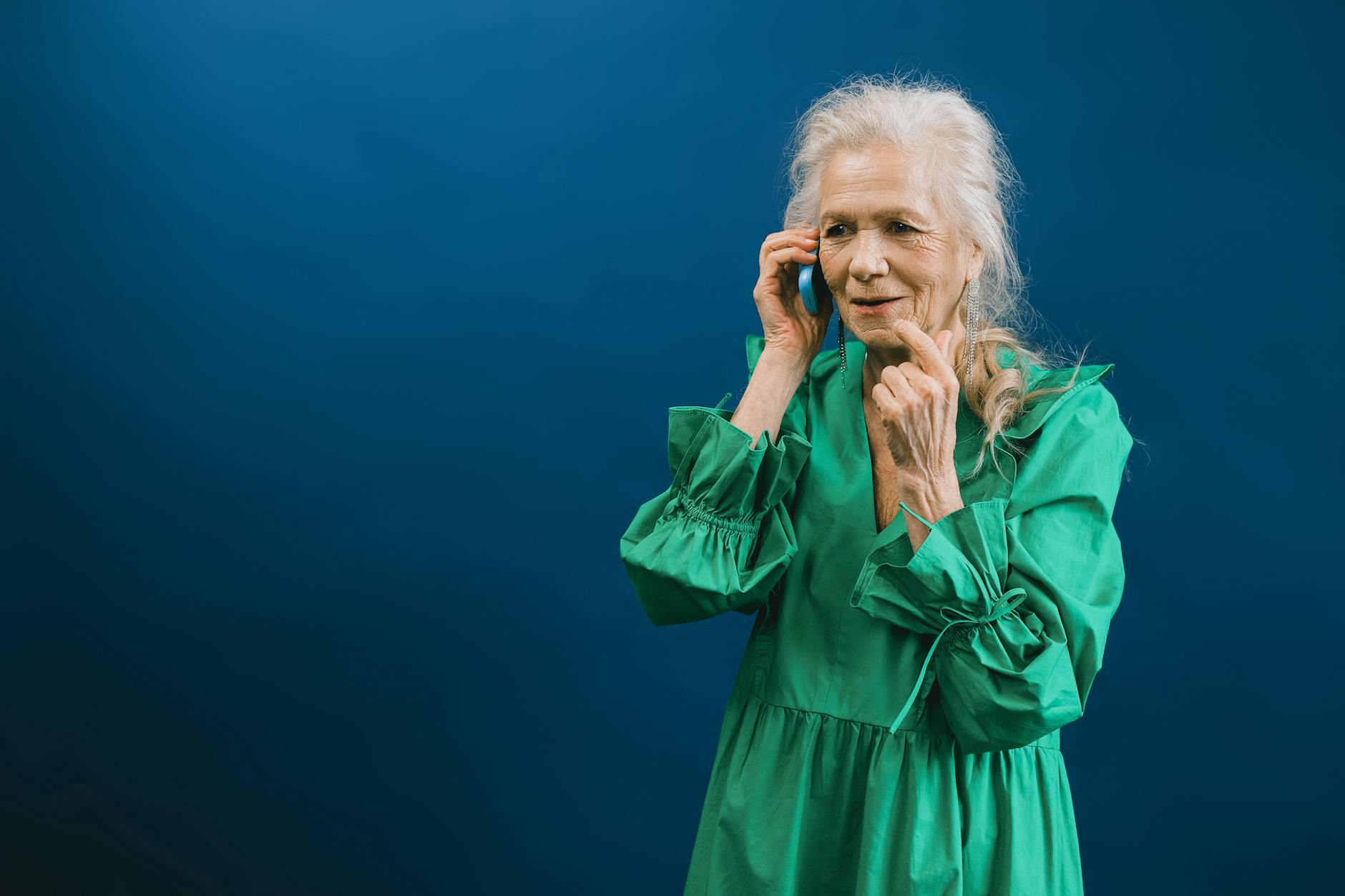 Senior woman wearing wireless earbuds while using smartphone