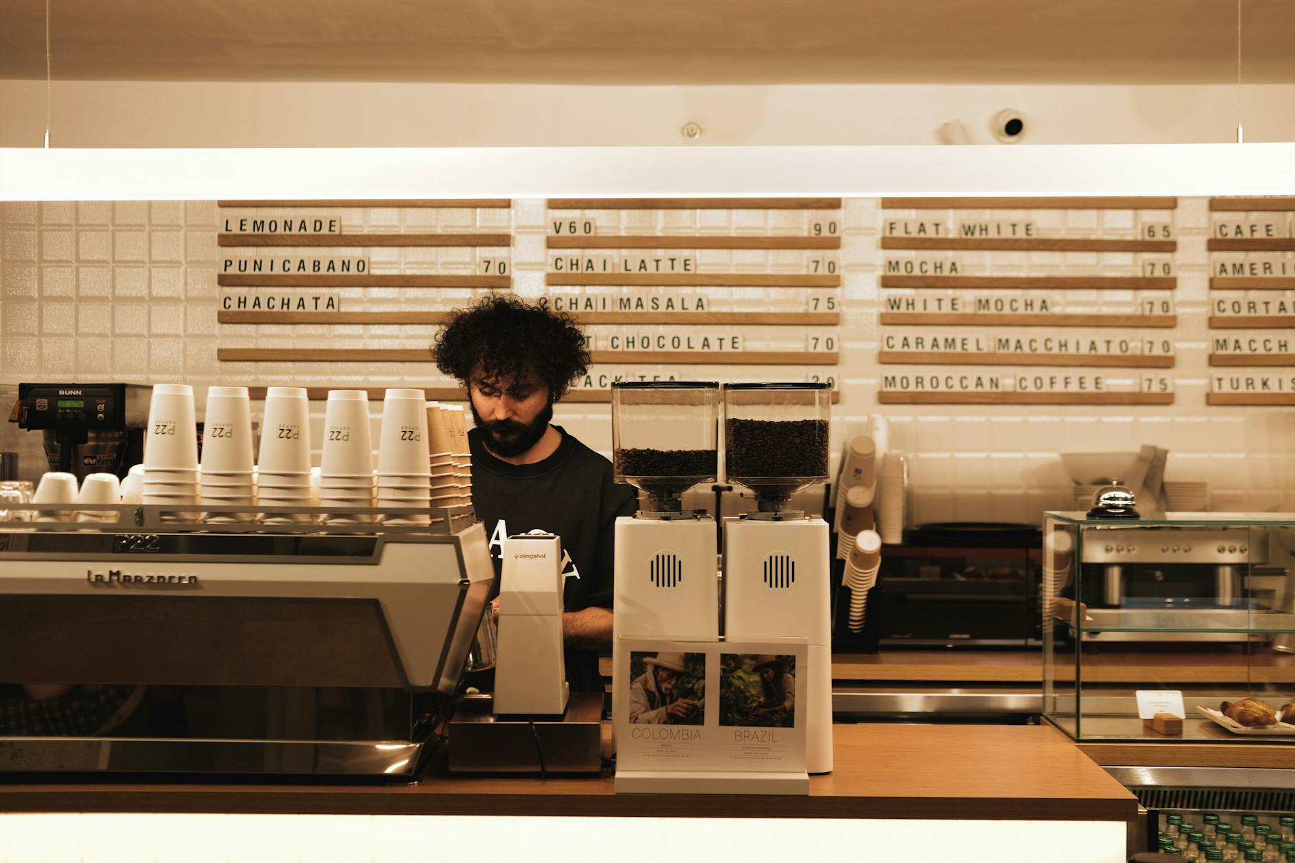 Interior of a busy coffee shop with people sitting at tables with laptops and drinks