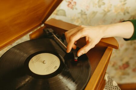 Close-up of vinyl records stacked next to a vintage turntable with stylus ready to play