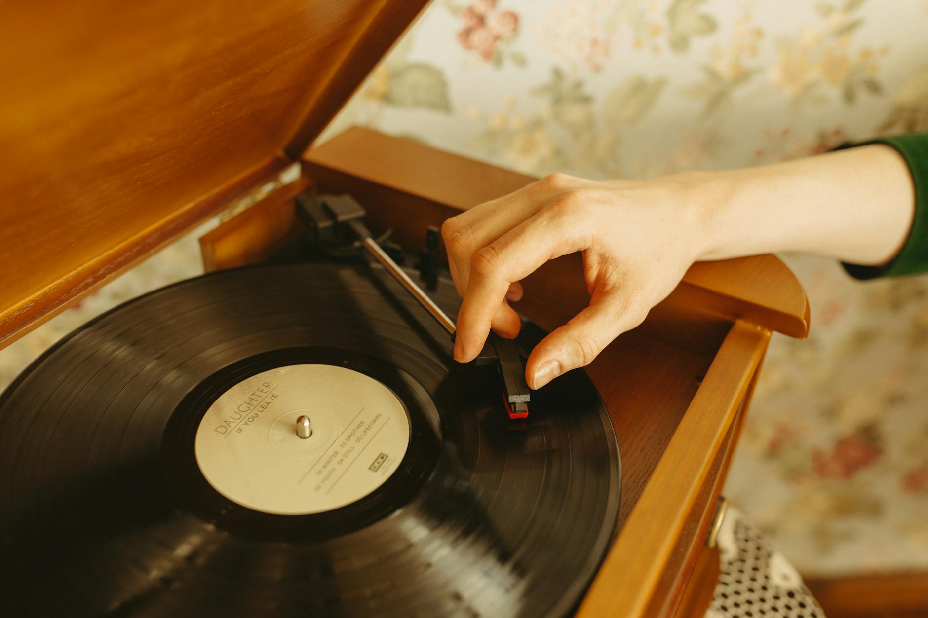 Close-up of vinyl records stacked next to a vintage turntable with stylus ready to play