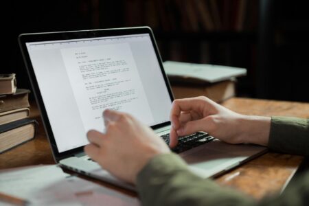 Person typing on laptop computer at desk, representing independent authors writing and self-publishing