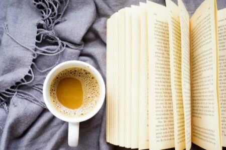 Stack of books arranged on wooden table with coffee cup and plants for social media flat lay
