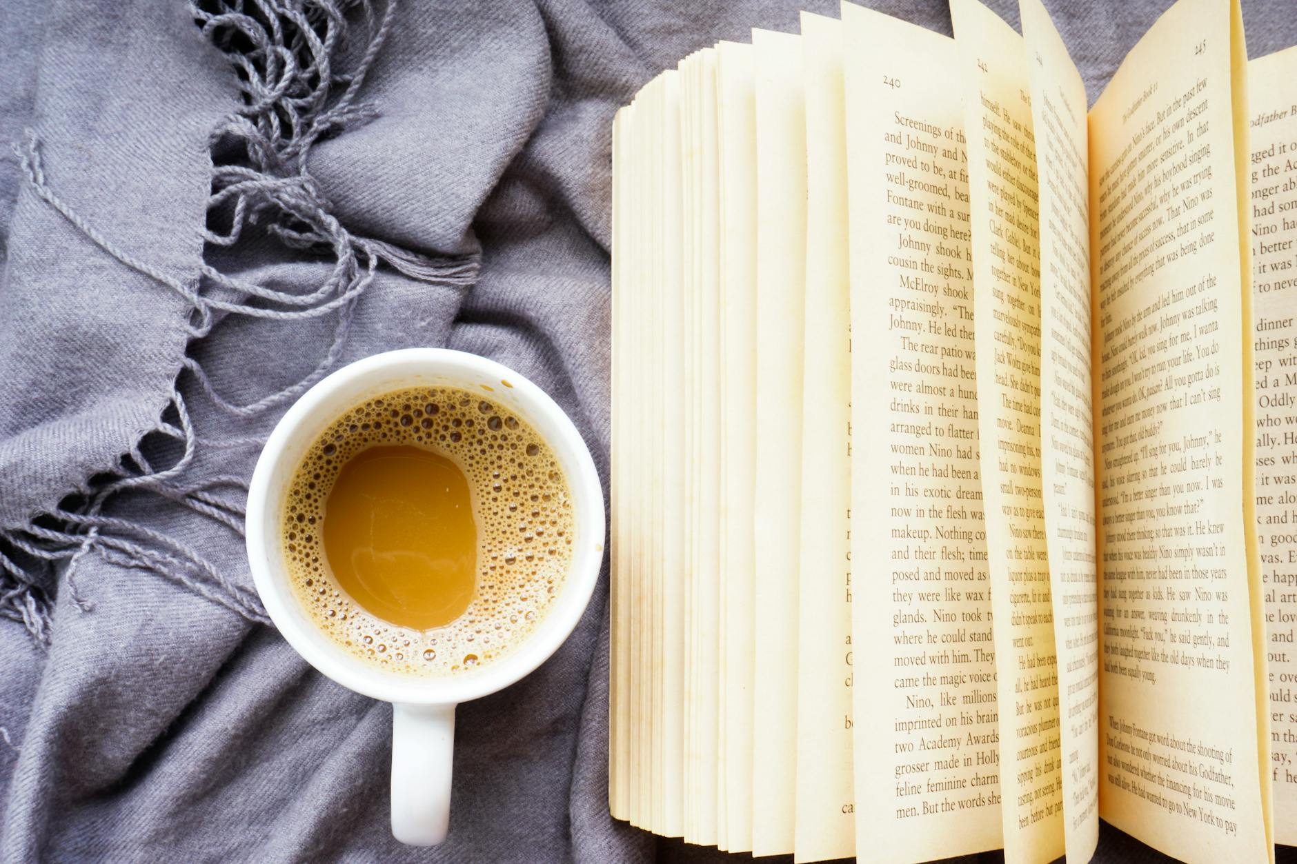 Stack of books arranged on wooden table with coffee cup and plants for social media flat lay