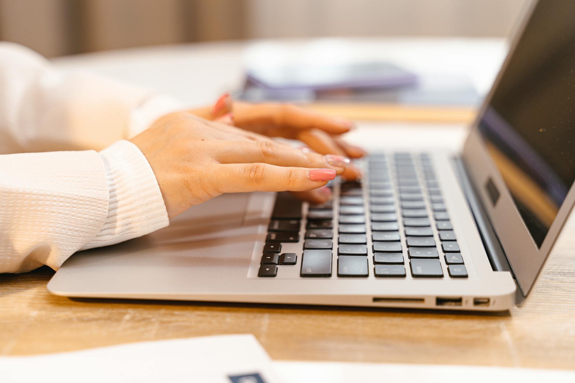 Person typing on laptop keyboard showing focused writing work