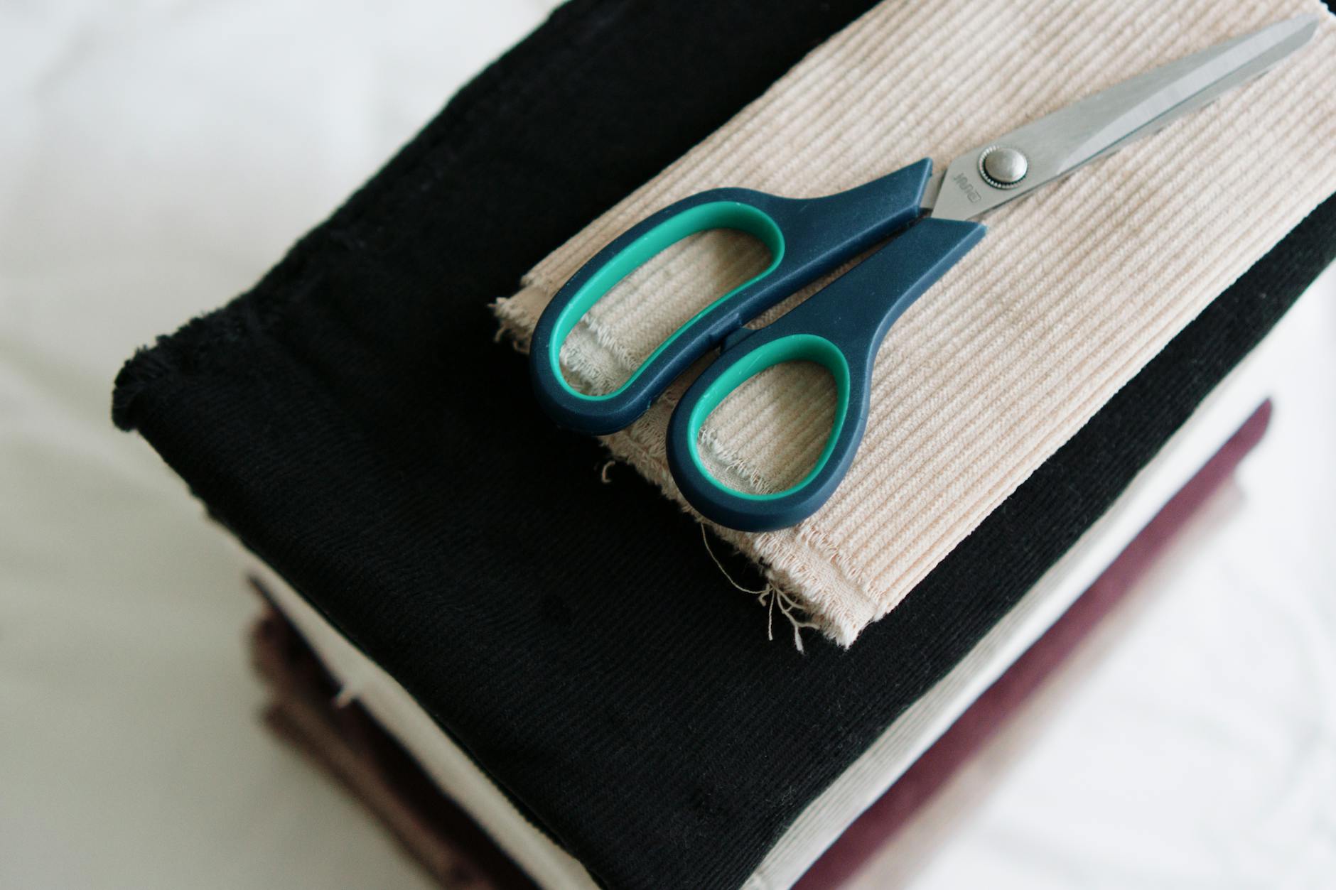 Hands cutting colorful fabric with professional sewing scissors on a cutting mat