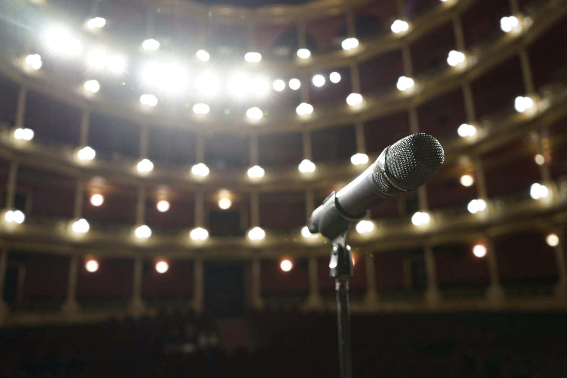 Vintage microphone on stage under bright spotlight in dark theater