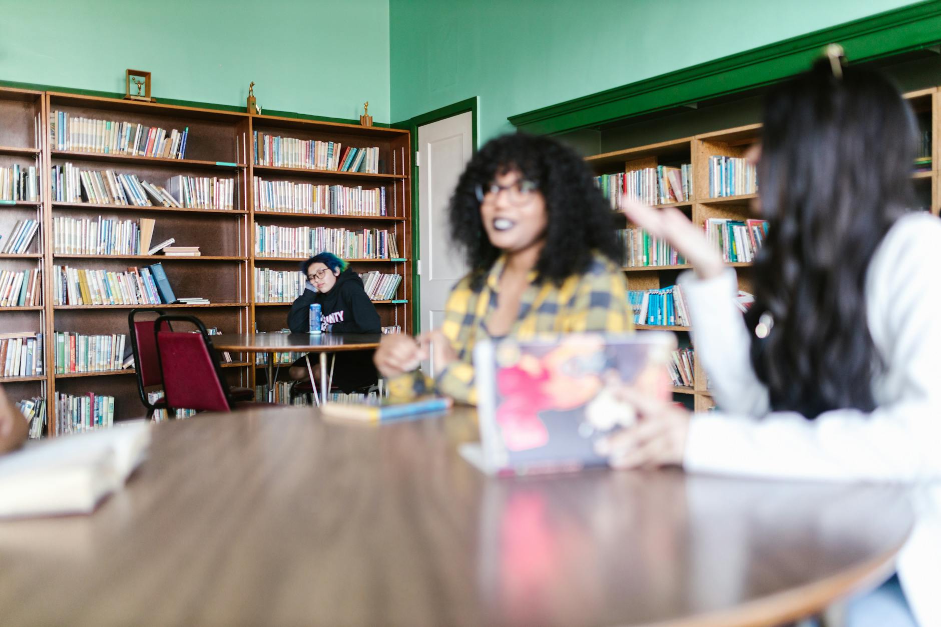 Group of diverse people sitting around table with books engaged in animated discussion