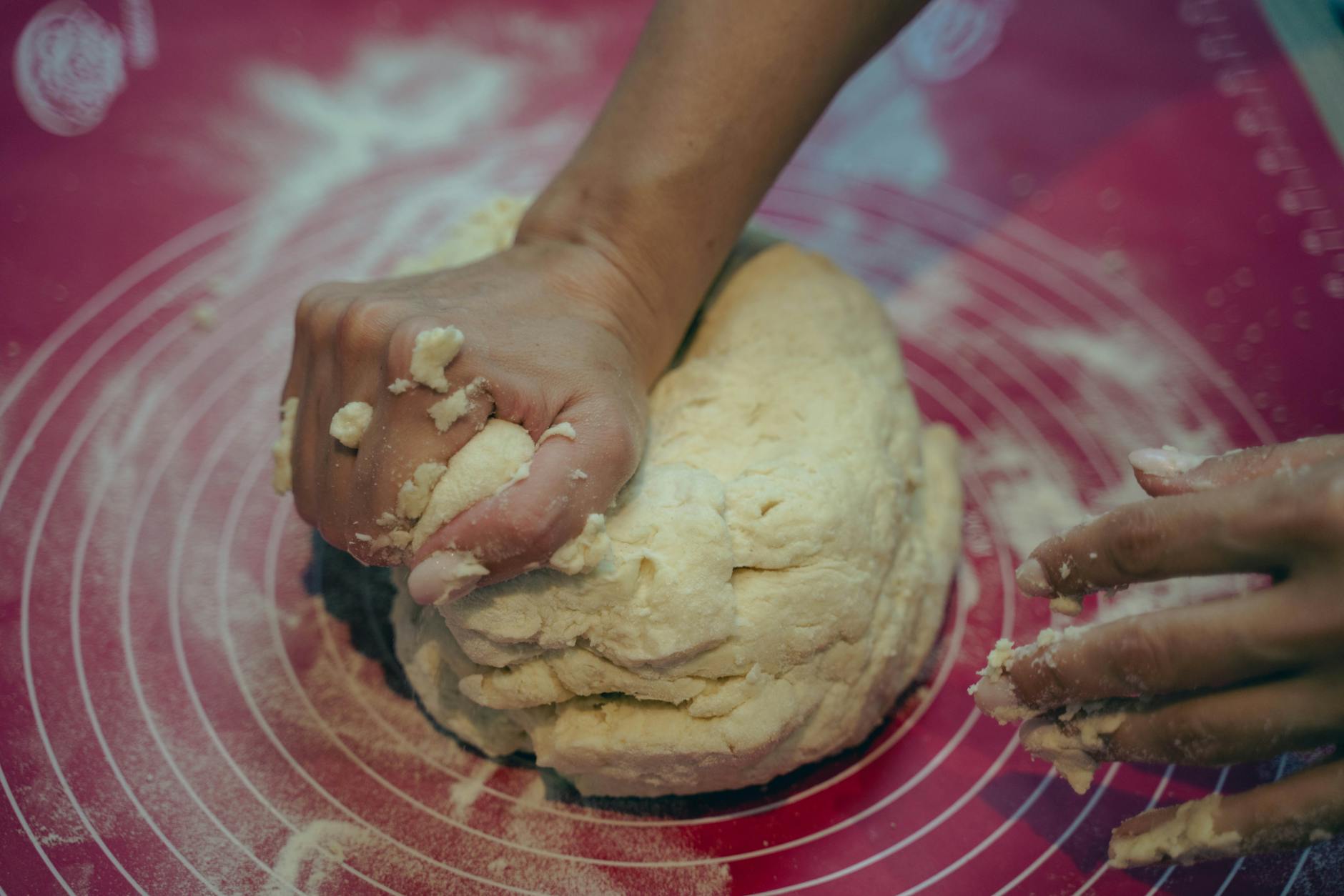 Close-up of hands kneading pasta dough on wooden cutting board