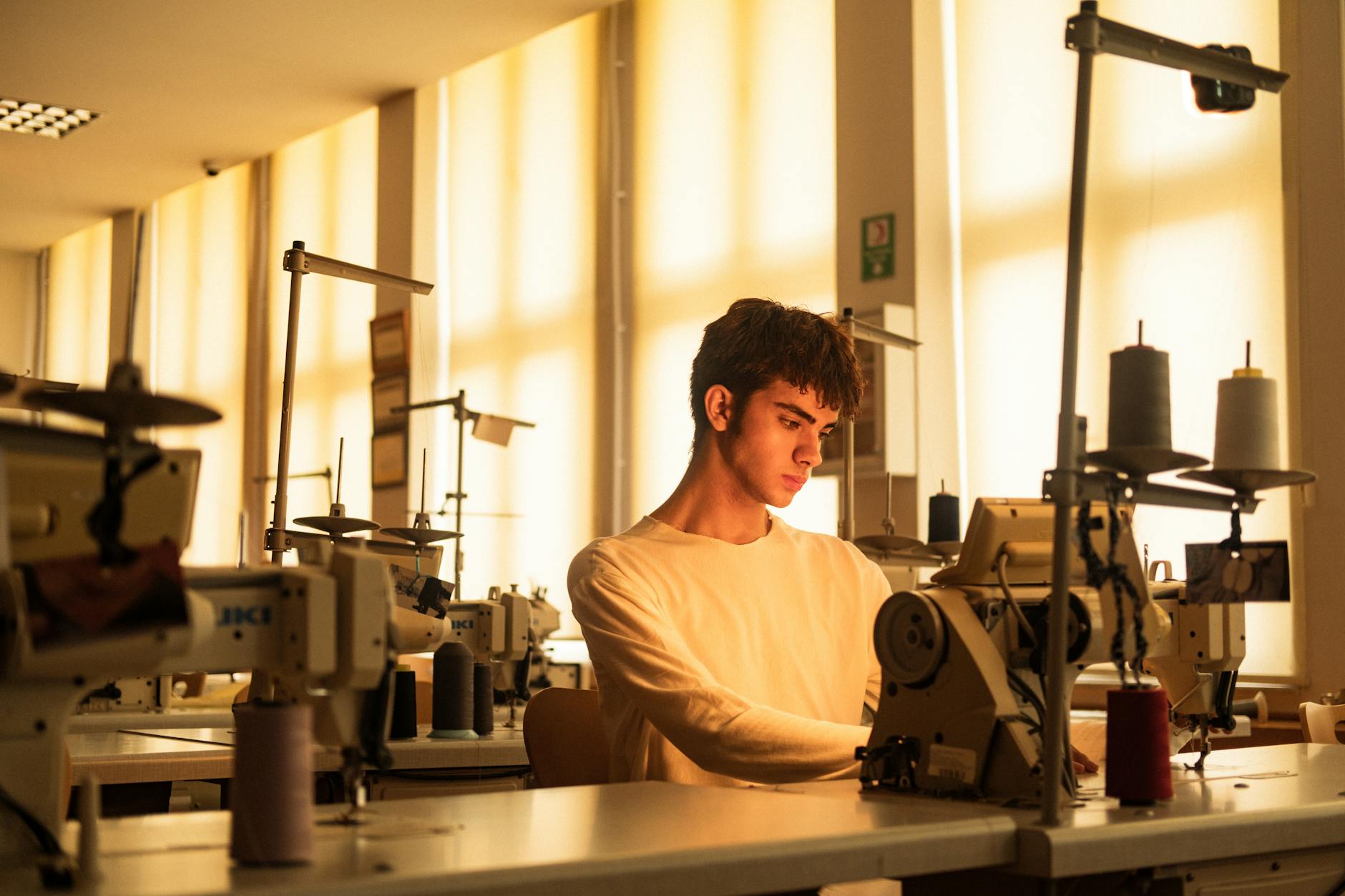 Students working on garment construction projects at tables in fashion classroom