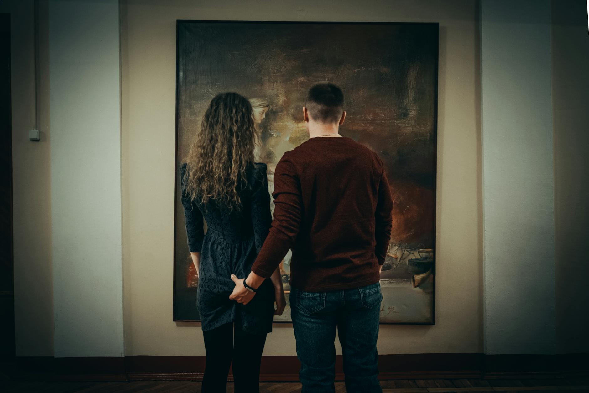 Young couple standing together viewing artwork in a contemporary gallery space with modern paintings on walls