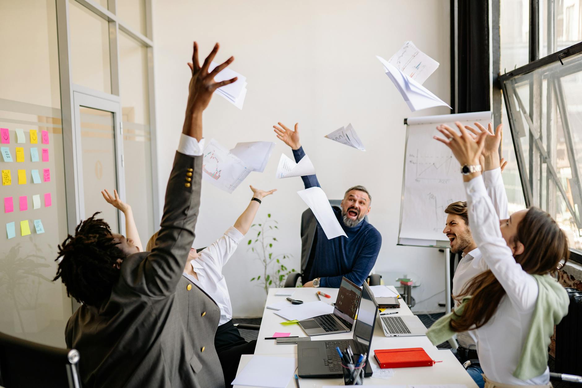 Happy office workers celebrating and laughing together in modern workspace