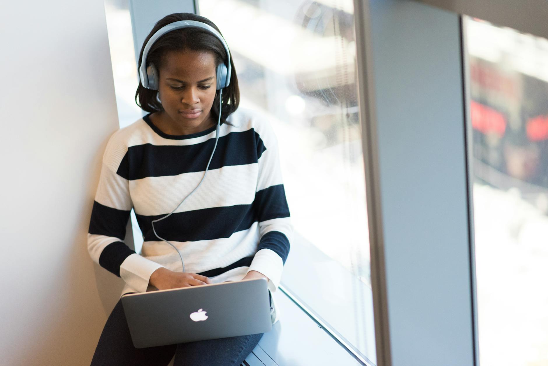 Person wearing headphones while using laptop, representing modern digital music listening experience