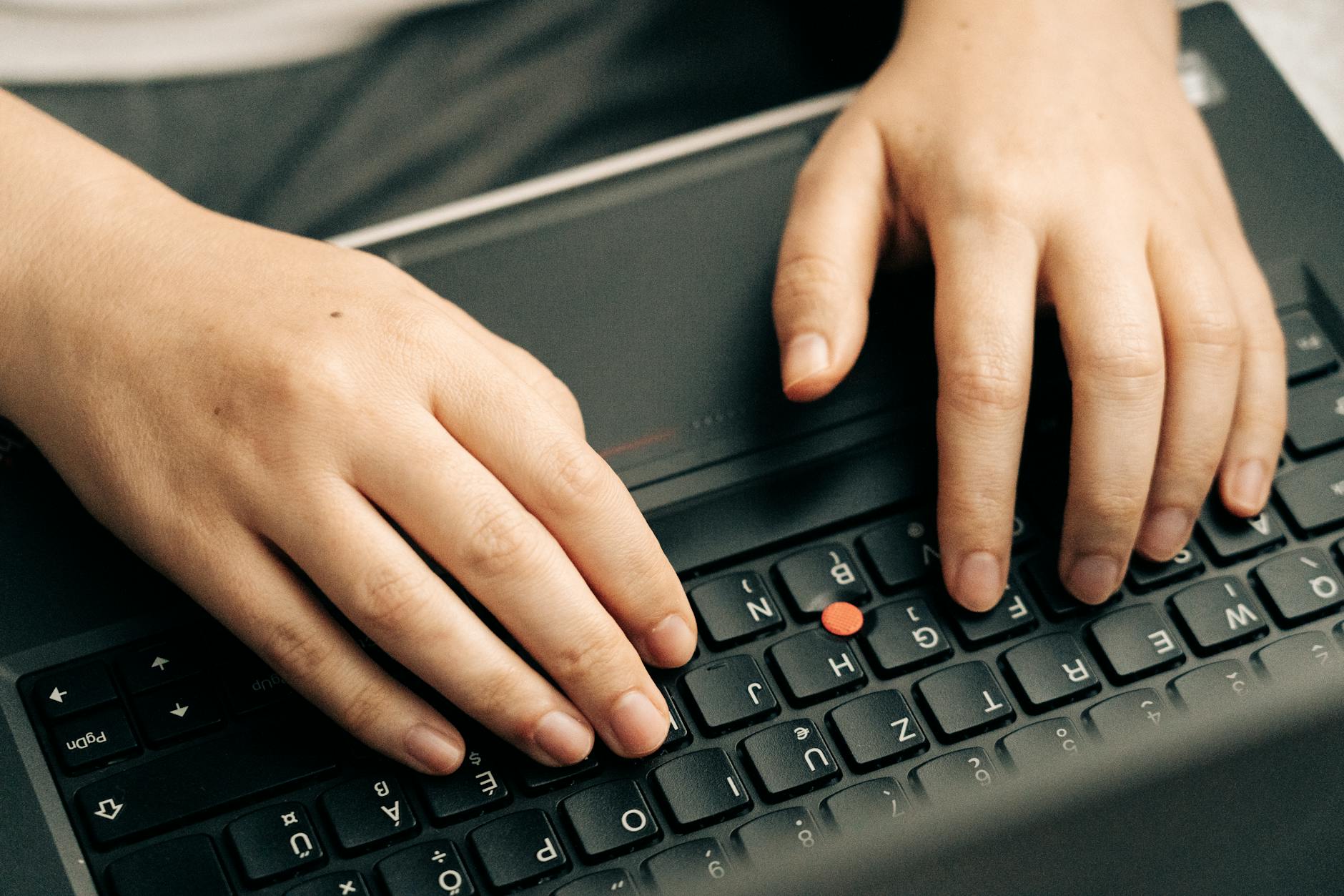 Close-up of hands typing on keyboard with screen glow