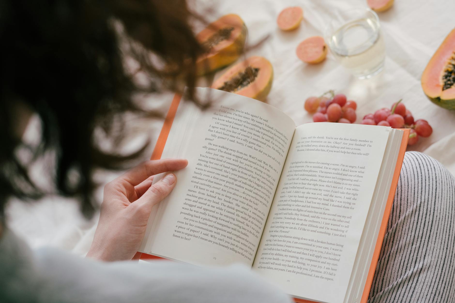 Person reading a book while surrounded by stacks of recommended books