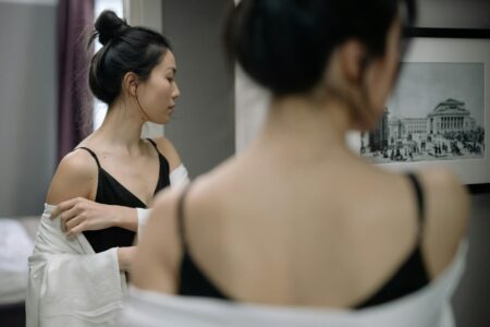 Asian woman looking at herself in a mirror, contemplating reflection