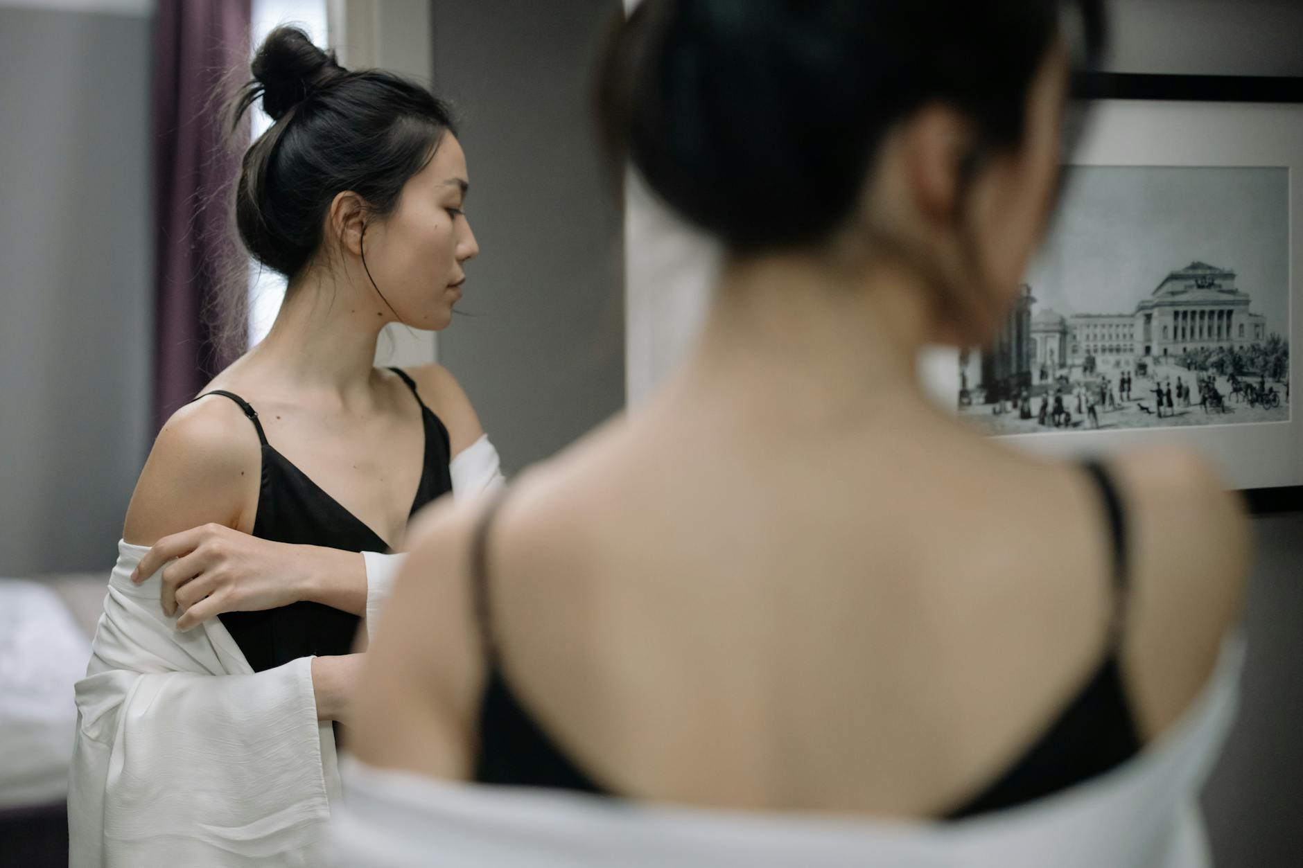 Asian woman looking at herself in a mirror, contemplating reflection
