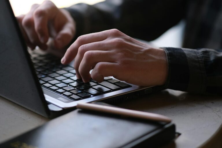 Person writing newsletter content on laptop with coffee cup nearby