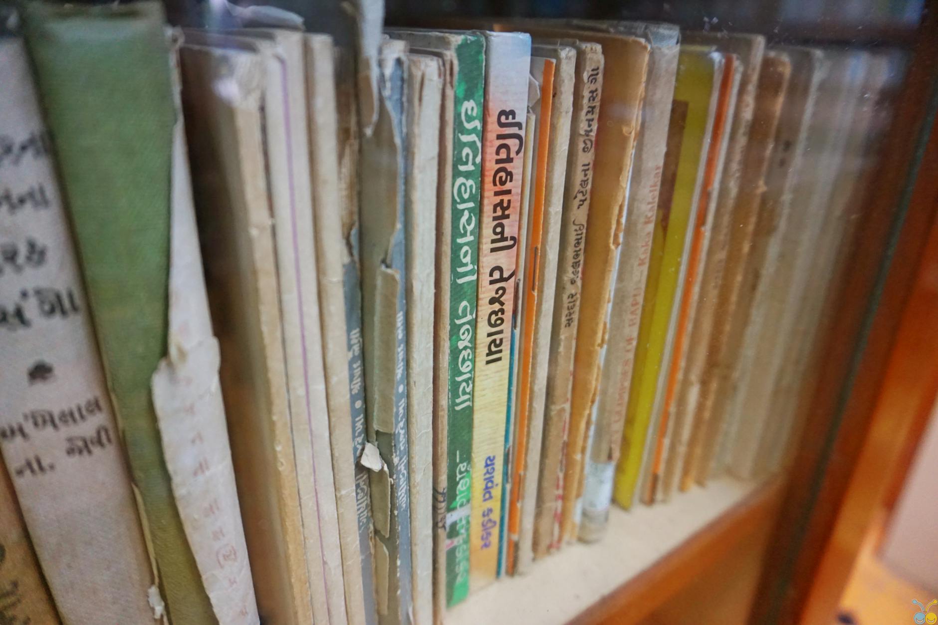 Rows of old hardcover books on a wooden library shelf
