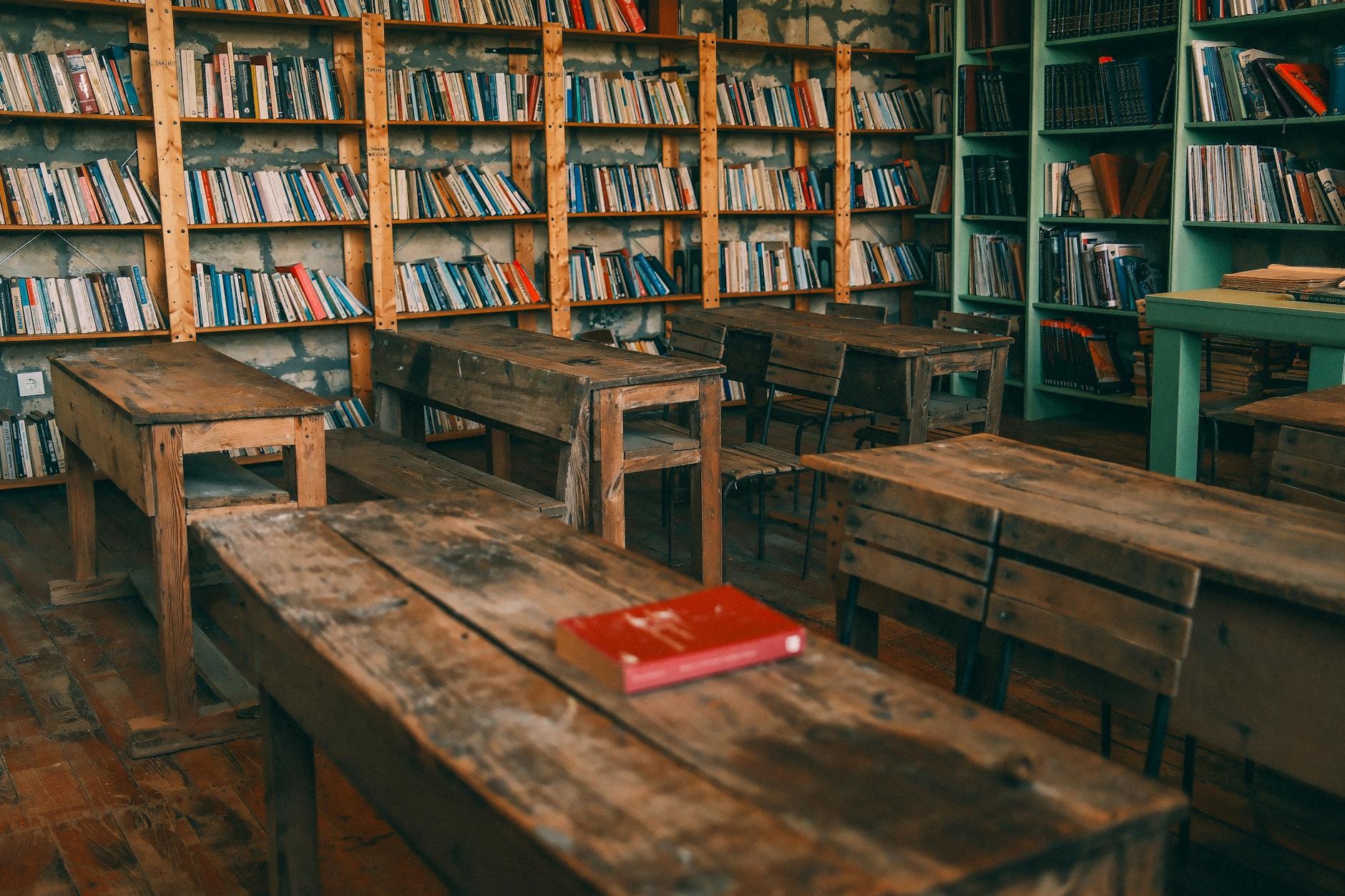 An old-fashioned classroom with wooden desks and large windows casting afternoon light