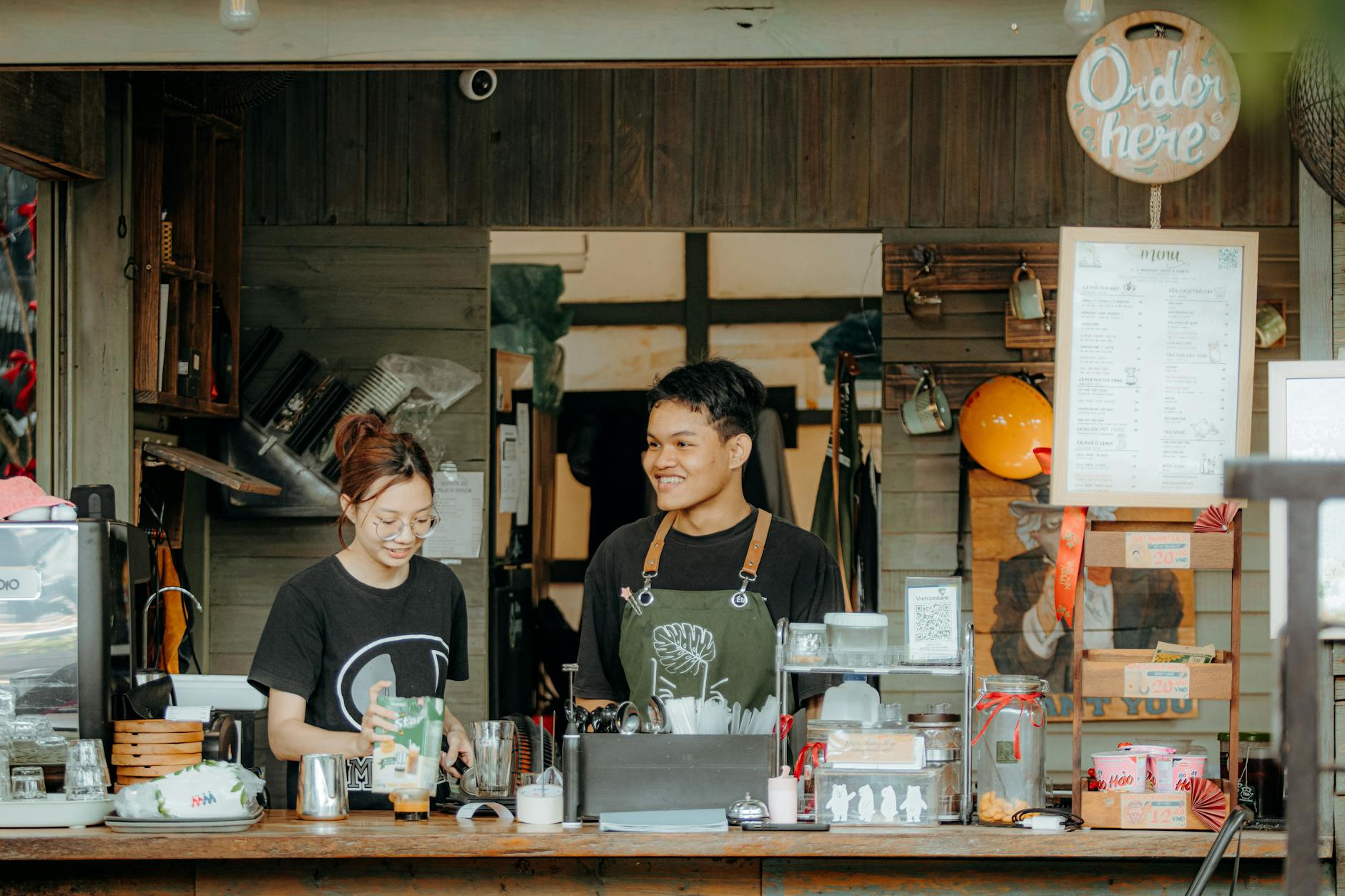 Busy urban coffee shop interior with customers working on laptops at wooden tables
