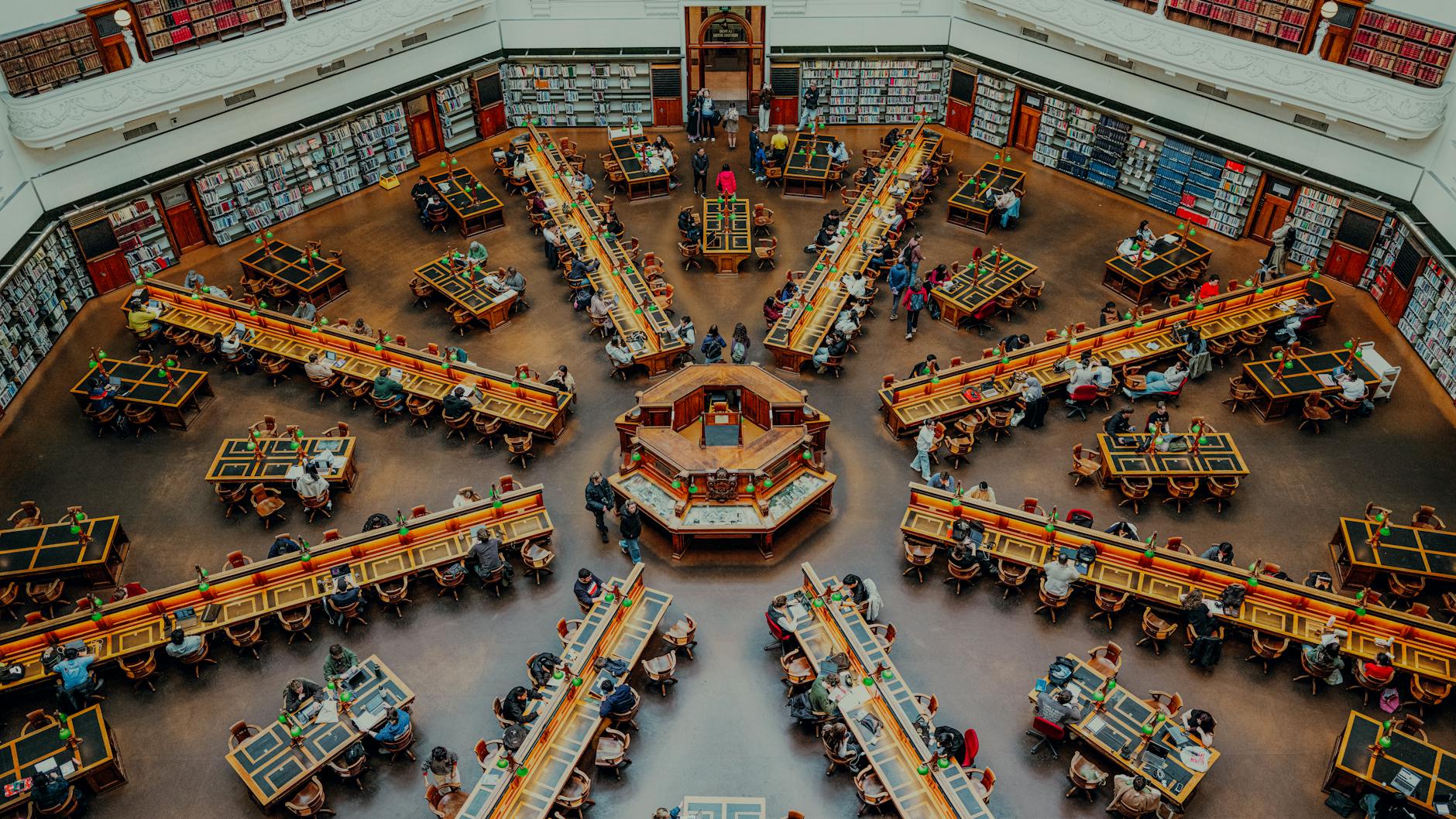 Quiet library reading room with wooden tables and bookshelves