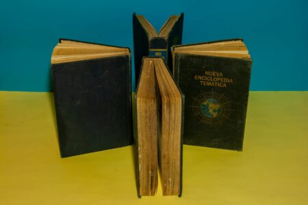 Stack of open vintage books on a wooden table suggesting literary history