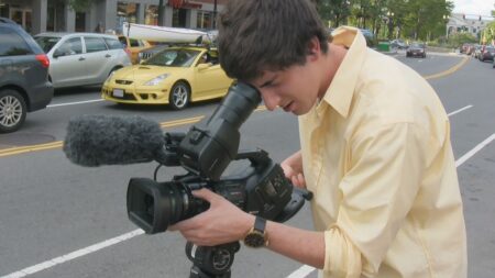 A handheld documentary film camera resting on a table in dim light