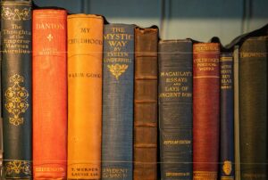 Stack of aged hardcover books with worn spines on a wooden surface