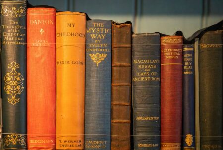 Stack of aged hardcover books with worn spines on a wooden surface