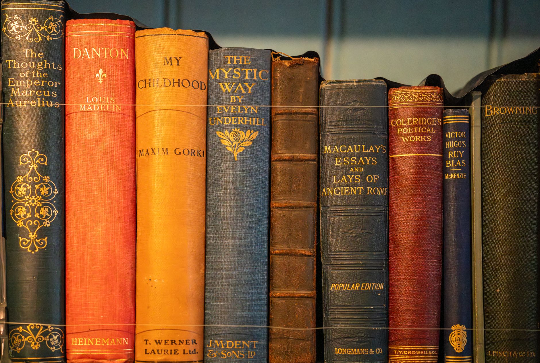 Stack of aged hardcover books with worn spines on a wooden surface