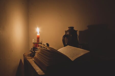 An open book beside a lit candle, evoking literary reflection and mourning